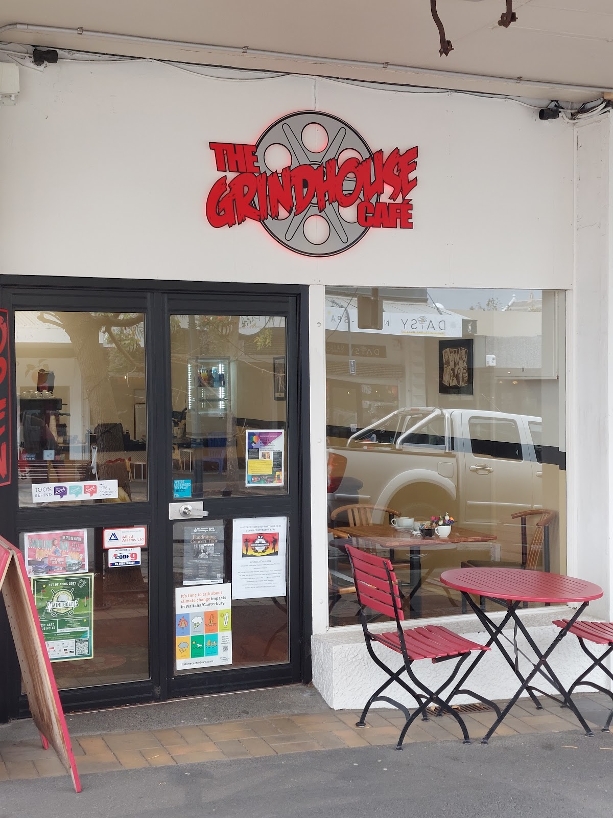 The Grindhouse Cafe shopfront with its film reel sign and red footpath tables