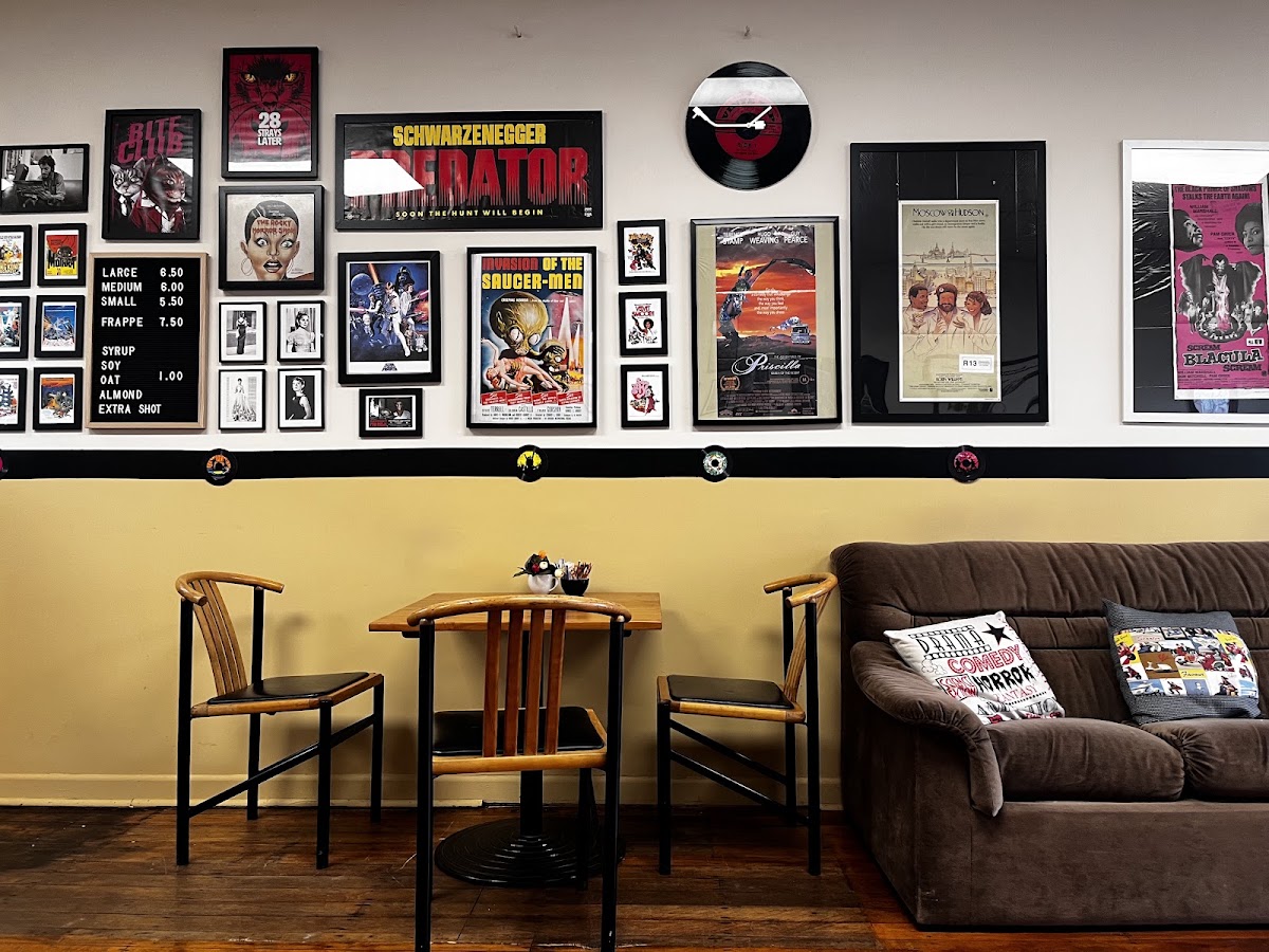 Poster wall with Predator and cult film posters above the sofa